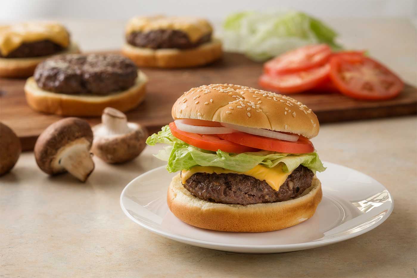 Blended burger topped with cheese, lettuce, tomato and onion on a sesame seed bun.